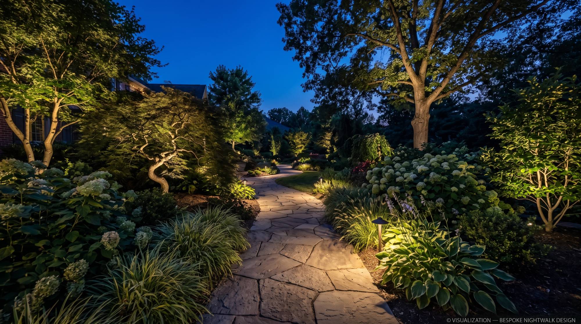 A flagstone path curving through planted borders at night, lit by low path lights, with a Japanese maple and mature trees uplit from beneath and hydrangeas glowing along both edges.